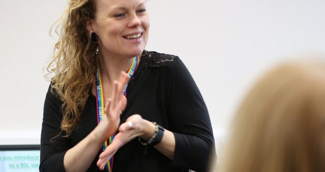 An image of a BSL tutor showing the BSL sign for happy