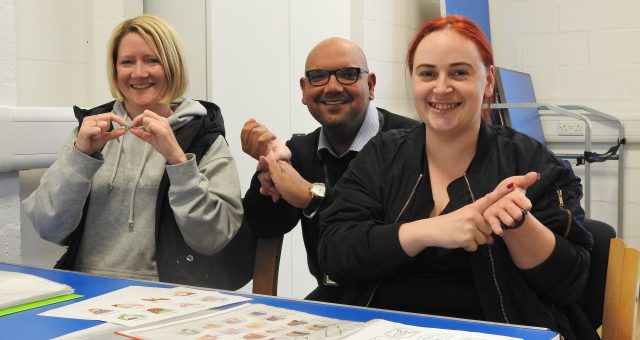 An image of two British Sign Language learners signing with their tutor