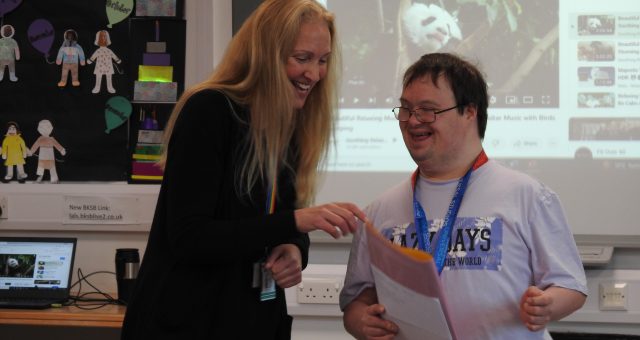 A tutor and a learner learning difficulties are laughing together.