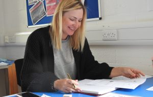 Learner is sitting at a desk looking over some practice exam questions.