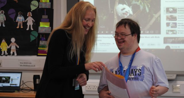 A tutor and a learner learning difficulties are laughing together.