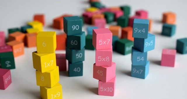 Image shows a cluster of colourful stacked 'dice' which show maths puzzles on as part of a fun maths game.