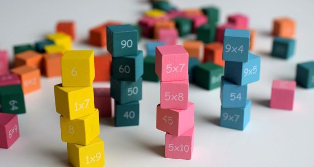 Image shows a cluster of colourful stacked 'dice' which show maths puzzles on as part of a fun maths game.